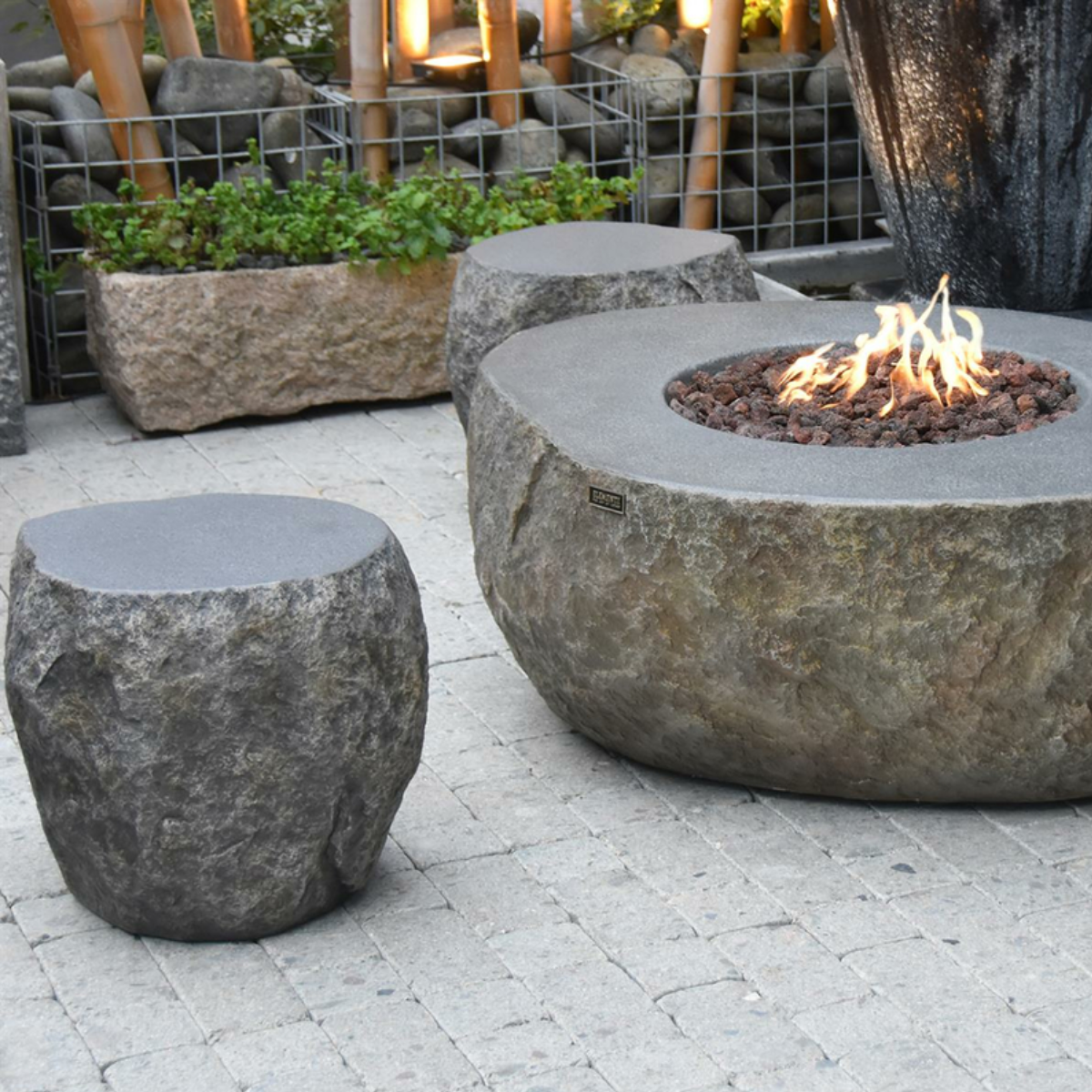 Sfeerfoto van een stenen vuurtafel met stenen krukken